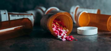 Open potje medicijnen verspreid over tafel